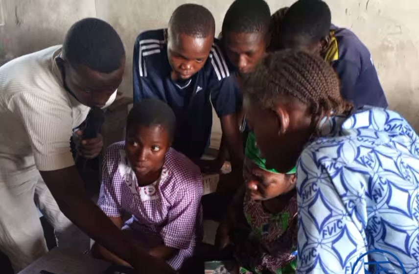 Young people gathered around a laptop with a Tech Now Global instructor during the first class in Badagry West, 2020